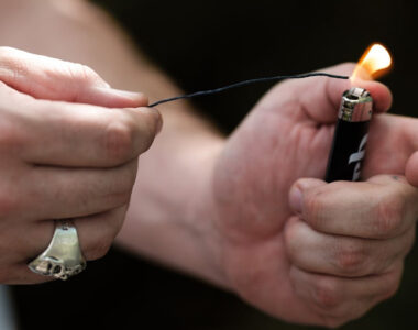 Jak używać knota konopnego – osoba trzymająca knot konopny, podpalając jego końcówkę za pomocą zapalniczki. Naturalna alternatywa dla zapalniczek i zapałek, zapewniająca czystsze spalanie i lepszy smak.